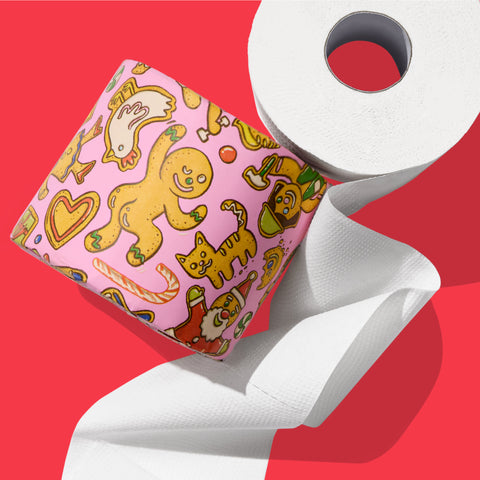 Close-up of a Who Gives a Crap toilet paper roll wrapped in festive paper featuring a gingerbread man illustration.