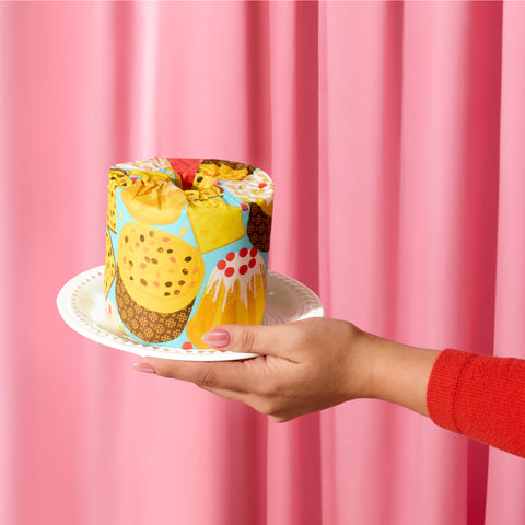 Close-up of a Who Gives a Crap toilet paper roll wrapped in festive paper featuring a cake illustration.