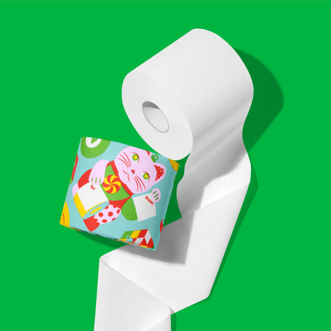 Close-up of an unrolled white roll of 3-ply bamboo toilet paper beside a roll in a festive wrapper, on a green background.